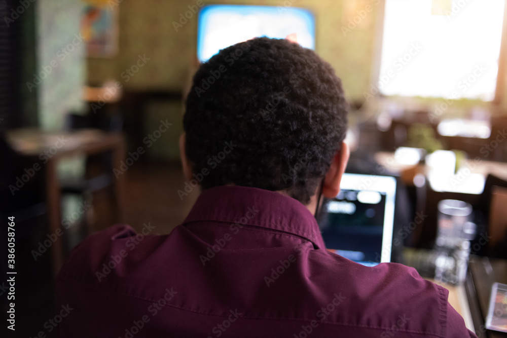 Young black male developer sitting in pizza restaurant, drinking coffee or tea and working with laptop. Young black male developer sitting in pizza restaurant, drinking coffee or tea and working with laptop.