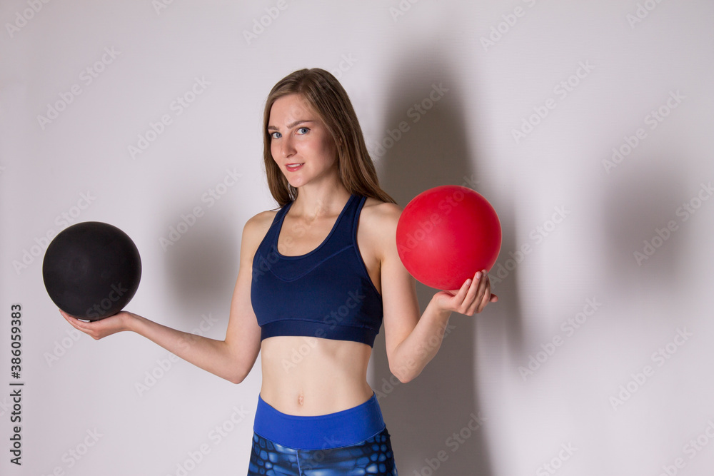 athletic girl in sports uniform holding red and black balloon on gray background