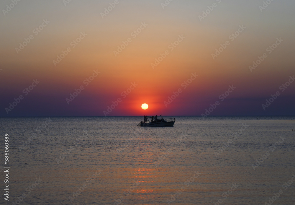 People admire the sea sunset while on board a pleasure boat. The evening sun hangs over the ship.