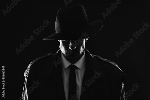 Tablou pe pânză Old fashioned detective in hat on dark background, black and white effect