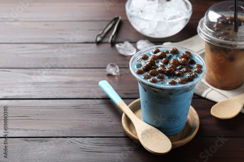 Tasty blue milk bubble tea and spoon on brown wooden table. Space for text