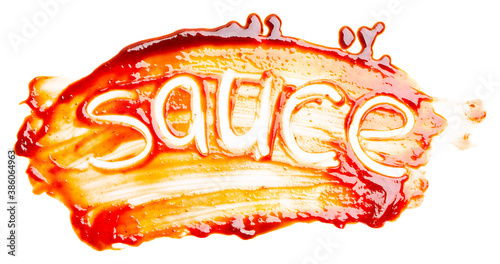 The word SAUCE written with finger on the spilled sauce isolated on white background. Top view, close up.