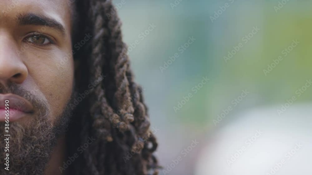 Half face portrait of attractive black male with long hair looking to camera with a serious expression