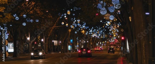 Night view of a city street with Christmas lights and decorations. Slow motion, wide shot. 