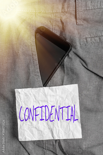 Text sign showing Confidential. Business photo text containing an individualal information whose unauthorized disclosure Smartphone device inside formal work trousers front pocket near note paper photo