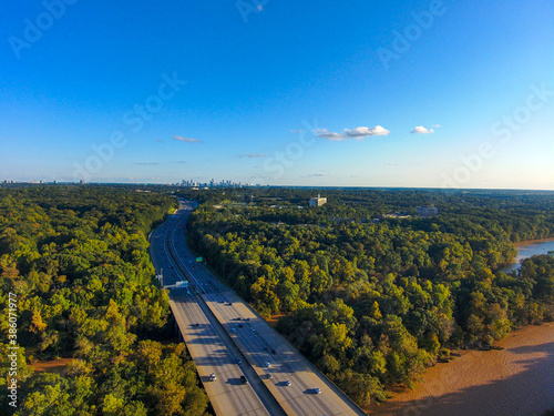 a stunning aerial shot of vast miles of lush green trees, the freeway, the Chattahoochee river and blue sky at sunset at the Chattahoochee River National Recreation Area in Sandy Springs Georgia