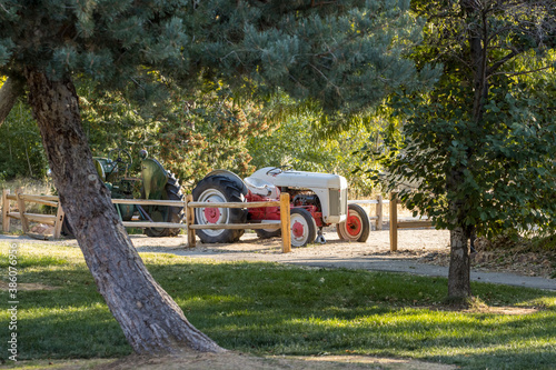 Two tractors parked behind a wood stick fence in a park