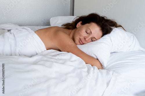 Beautiful young brunette woman sleeping in a white bed.