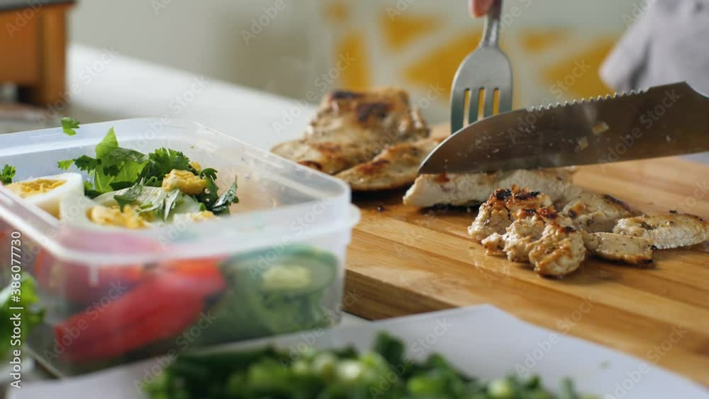 Woman preparing healthy vegetable chicken salad in the home kitchen.