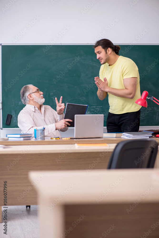 Old teacher and young male student in the classroom Old teacher and young male student in the classroom