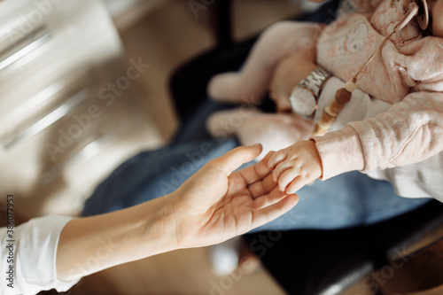 Close up of beautiful little hand with tiny fingers of adorable newborn baby girl, in caring mother arms, happy family moments, motherhood and childhood concept