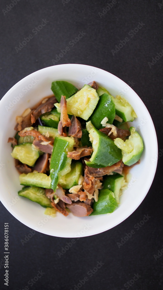 Chinese salad of broken fresh cucumbers with pieces of meat and sauce.