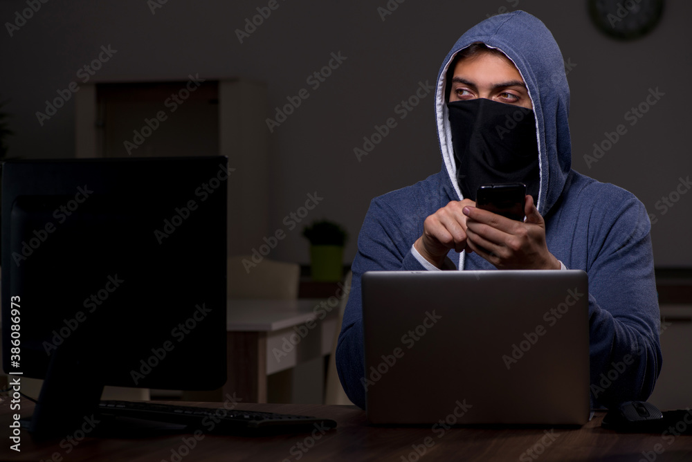 Male hacker hacking security firewall late in office Male hacker hacking security firewall late in office