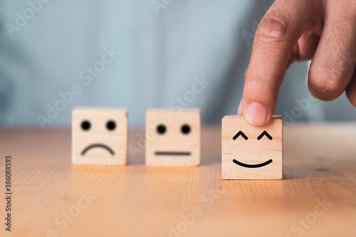 Select emotion or mood concept , Hand holding smile face  or happy face which print screen on wooden cube block. photo