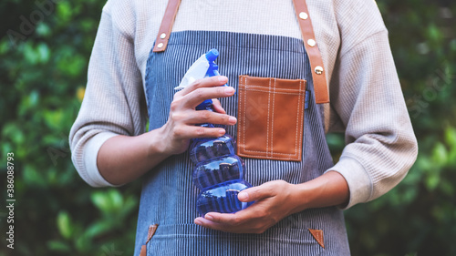 A female housekeeper with apron holding foggy spray bottle in garden