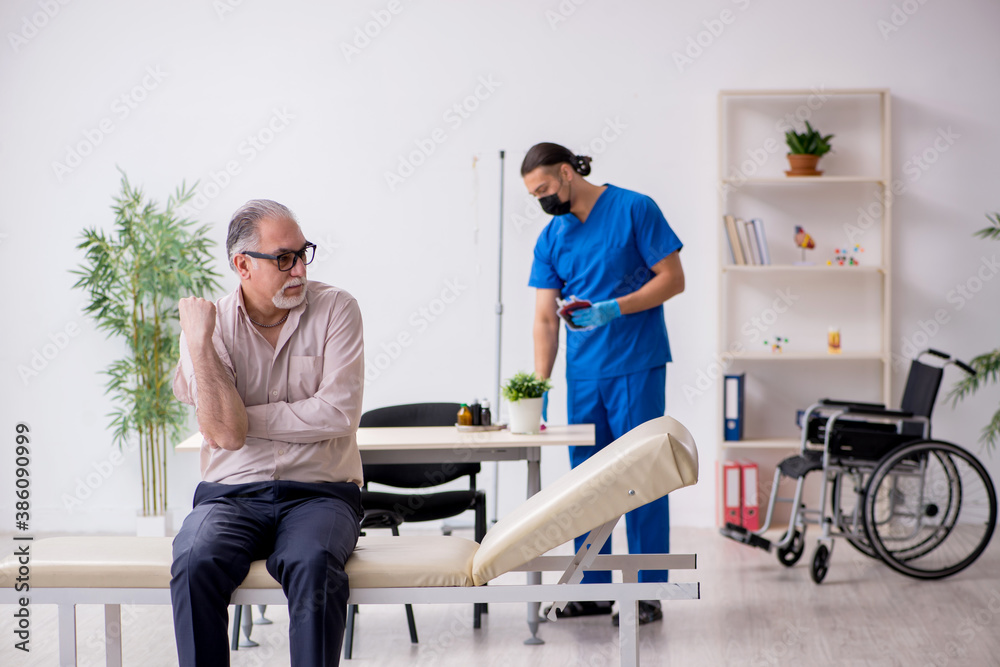 Old patient visiting young male doctor in blood sampling concept Old patient visiting young male doctor in blood sampling concept