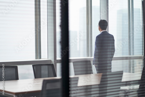 asian corporate executive standing in front of window thinking photo