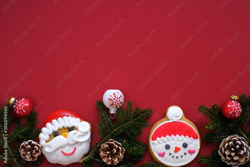 Christmas and New Years  holiday. santa claus and snowman christmas gingerbread cookies with fir branches and cones, christmas balls on a bright burgundy background.Sweets for the winter holidays. 