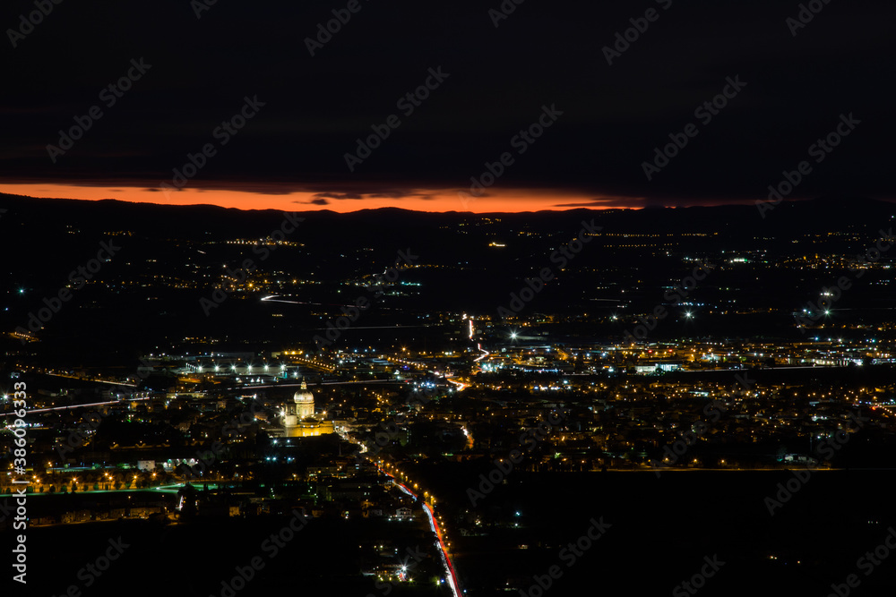 Aerial view of Umbria (Italy) valley at night, with city lights and S.M.degli Angeli Assisi church