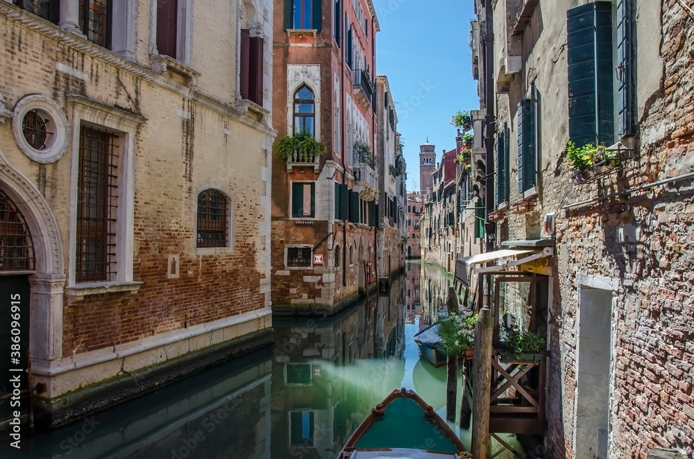 Narrow canal with old colorful houses in Venice, Italy. Traditional gondola in Venetian water canal. Narrow canal street with colorful buildings and boats in Venice.