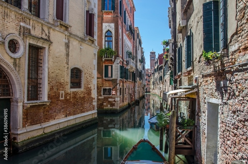 Narrow canal with old colorful houses in Venice, Italy. Traditional gondola in Venetian water canal. Narrow canal street with colorful buildings and boats in Venice. © Maria Vonotna