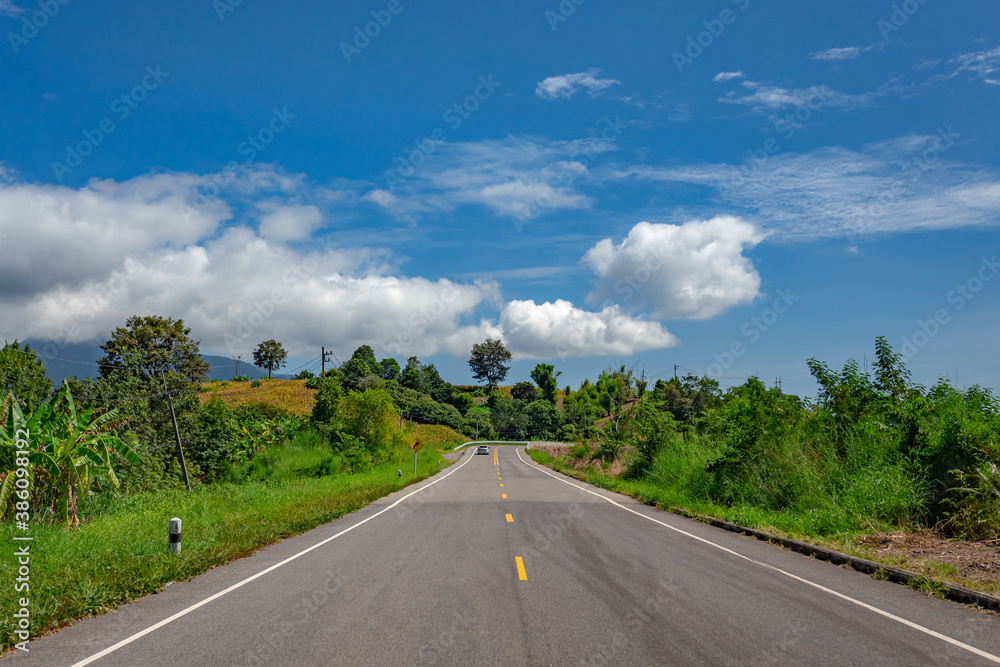 Rural Country Road on the Rush Green Forest Mountain range  under blue sky at Doi Phuka National Reserved Park, Nan Province, Thailand