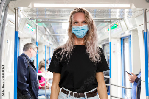 Young blonde woman in a mediuinskaya mask in a subway car. Coronavirus pandemic.