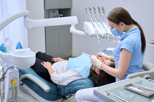 Woman doctor dentist treating teeth to patient in dental chair