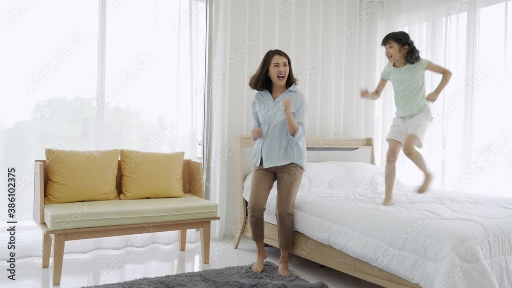 Asian mom and daughter having fun playing dancing in bed room Asian mom and daughter having fun playing dancing in bed room