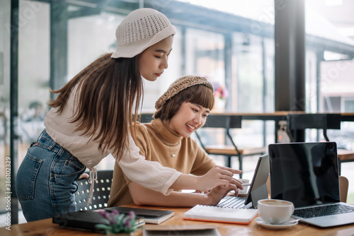 Two young asian woman talking and working together at office.