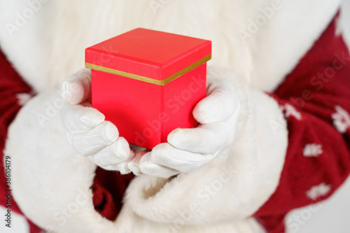 Santa Claus is holding a gift in his hand, his face is not visible. Isolated on white