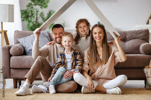 concept housing young family. mother father and children under fake roof in new home.