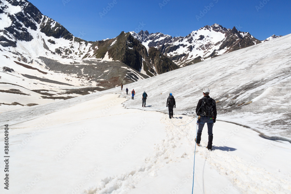 Rope team mountaineering with crampons on glacier Taschachferner and mountain snow panorama with blue sky in Tyrol Alps, Austria