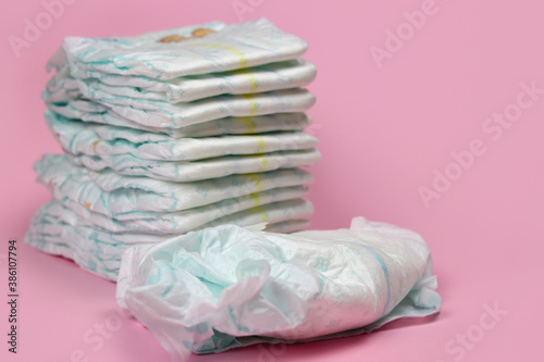 stack of diapers on a pink background, baby hygiene products. Selective focus