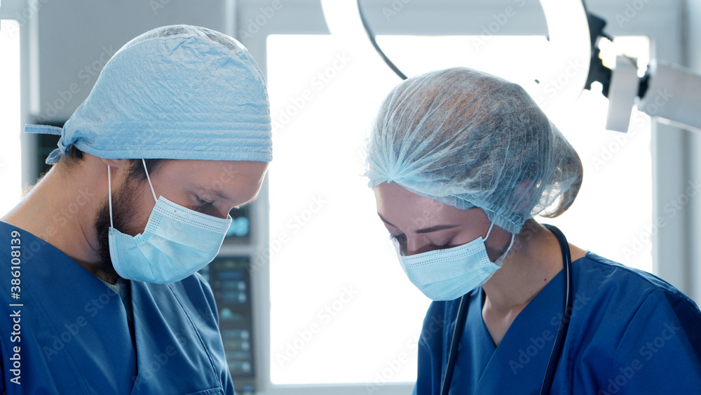 Professional medical doctors working in emergency medicine. Portrait of the surgeon and the nurse in protective masks performing surgical operation. Professional medical doctors working in emergency medicine. Portrait of the surgeon and the nurse in protective masks performing surgical operation.