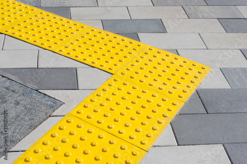 Yellow blocks of tactile paving for blind handicap. Braille blocks, tactile tiles for the visually impaired, Tenji blocks. Textured ground surface indicators located on sidewalks, stairs.