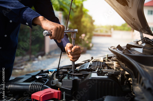 Close-up hands of auto mechanic are using the wrench to repair a car engine in auto car garage. Concepts of car care fixed repair and services.