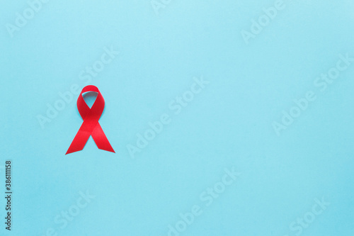 red AIDS awareness ribbon on the blue paper background. World aids day and healthcare and medicine concept
