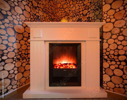 A burning fireplace in the room. White beautiful fireplace