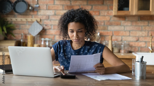 Tableau sur toile Serious millennial biracial woman calculate household expenditures finances on calculator at home