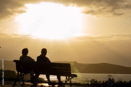 Silhouette of a couple sitting by the sea watching the sunset 