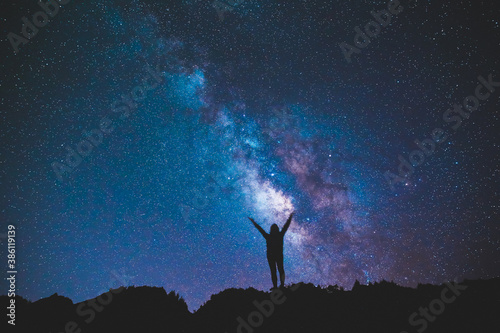 Silhouette of girl / woman standing on the hill. Stargazing at Oahu island, Hawaii. Starry night sky, Milky Way galaxy astrophotography.