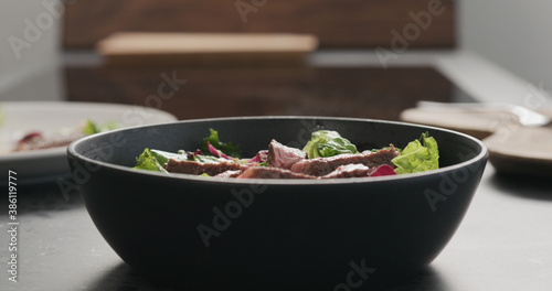 ribeye steak slices in salad in black bowl