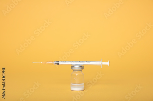 Syringe and ampules on yellow background.Vaccination.