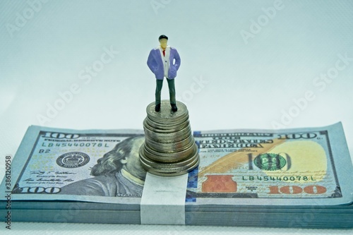 Man in a suit on top of a pile of coins in a white background