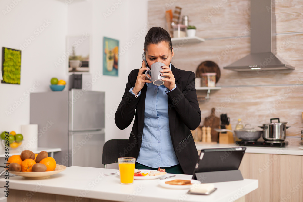 Business woman having a stressful work day. Concentrated business woman in the morning multitasking in the kitchen before going to the office, stressful way of life, career and goals to meet
