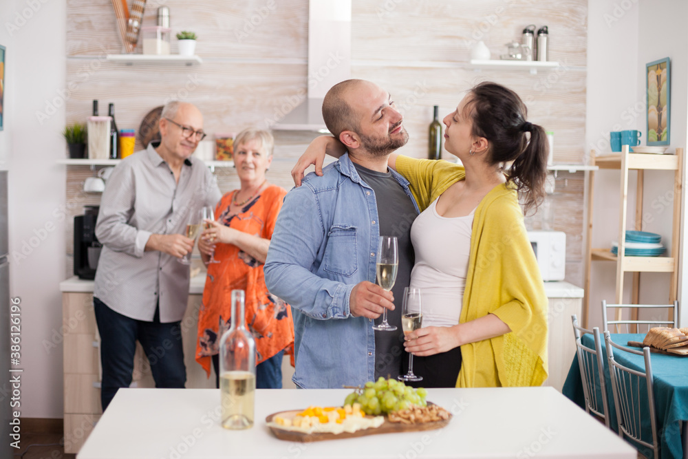 Couple looking at each other in kitchen during family brunch. Man holding glass of wine. Appetizer with various cheese. Couple looking at each other in kitchen during family brunch. Man holding glass of wine. Appetizer with various cheese.
