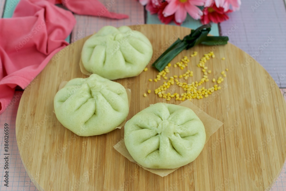 Fresh steamed Pandanus bread buns, filled with mung bean paste on wooden board