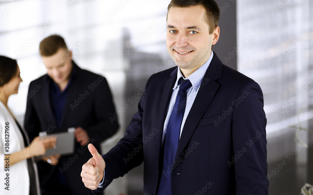 Portrait of a successful middle aged businessman, who is enjoying a good result of a teamwork, while standing at meeting in an office. Concept of success in a business Portrait of a successful middle aged businessman, who is enjoying a good result of a teamwork, while standing at meeting in an office. Concept of success in a business