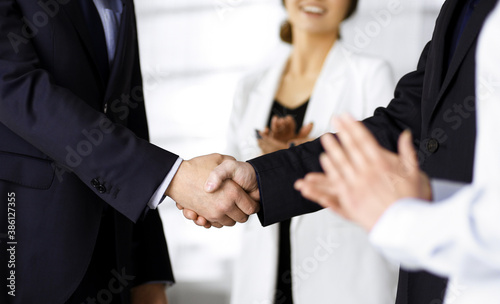 Unknown businesspeople are shaking their hands after signing a contract at meeting, close-up. Business communication concept